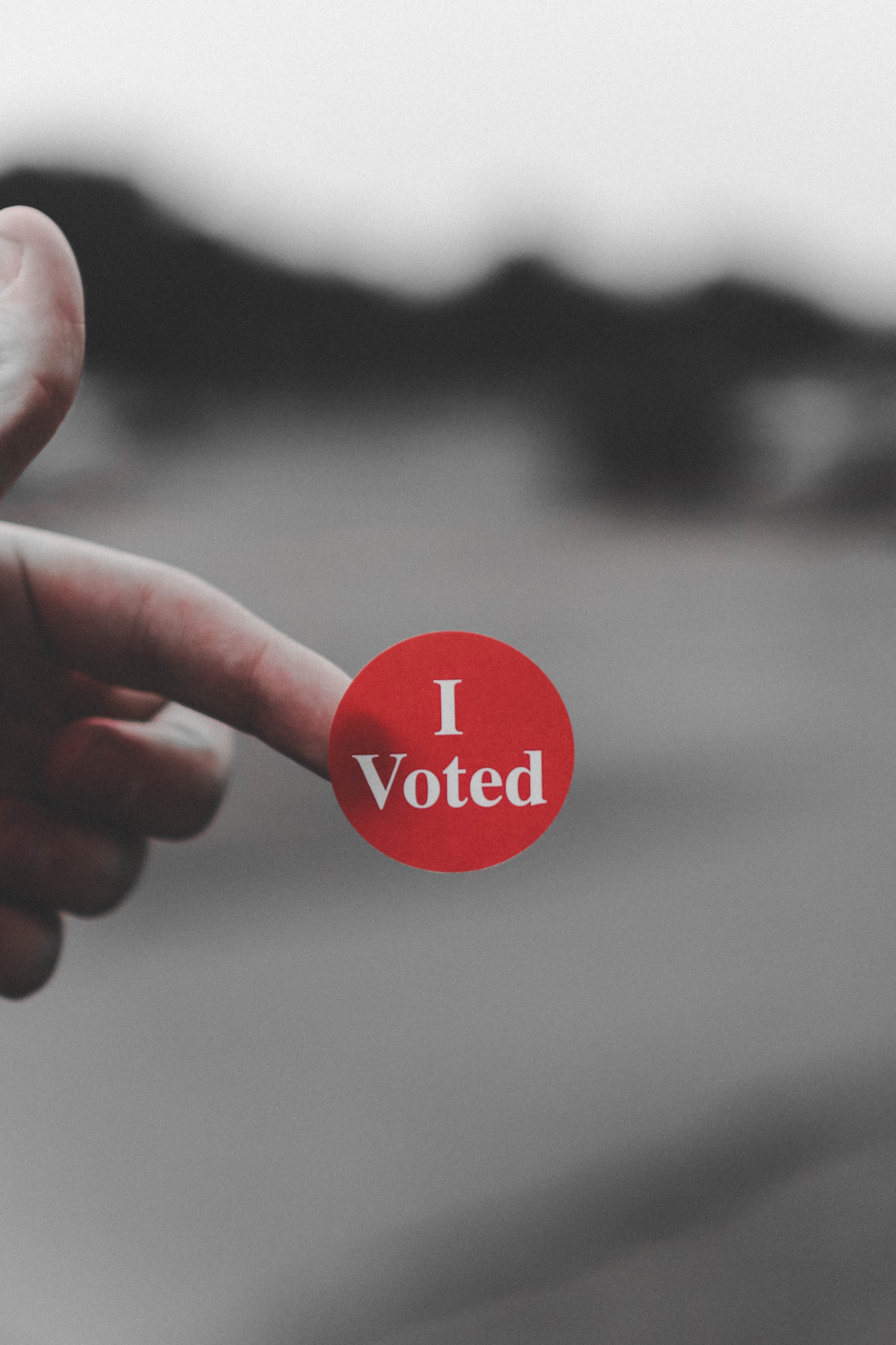 Person holding red "I Voted" sticker
