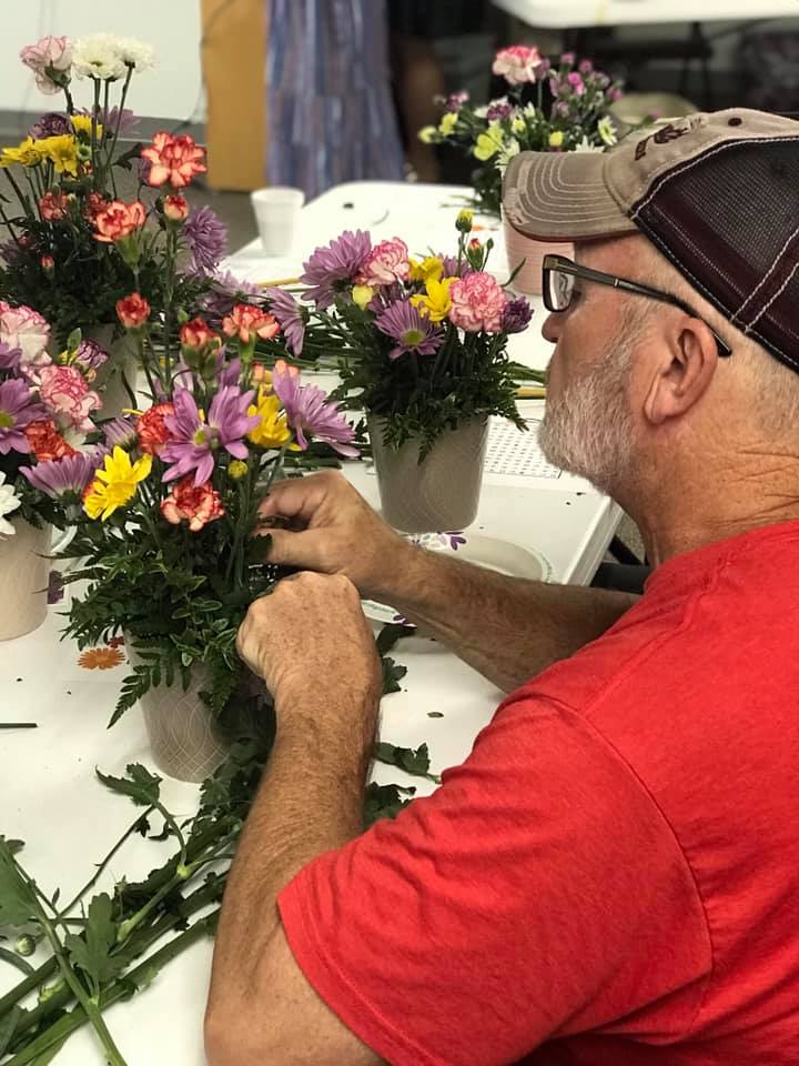 Man in red shirt arranging flowers in a vase