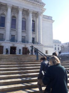 Several people climb steps of Capitol building in Madison