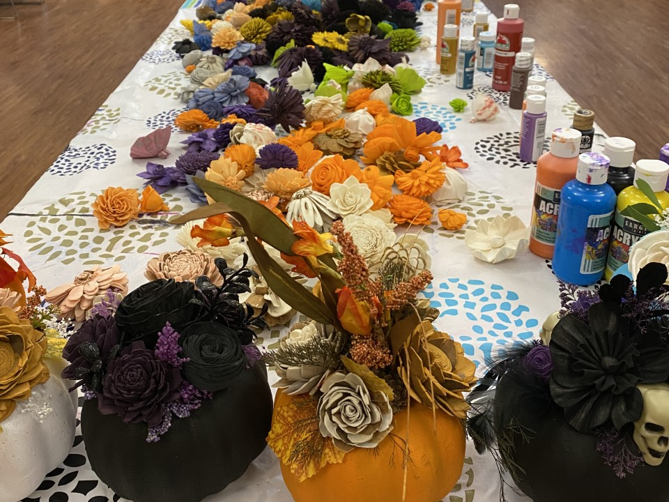 A table filled with craft supplies. Several decorated pumpkins sit at the end of the table.