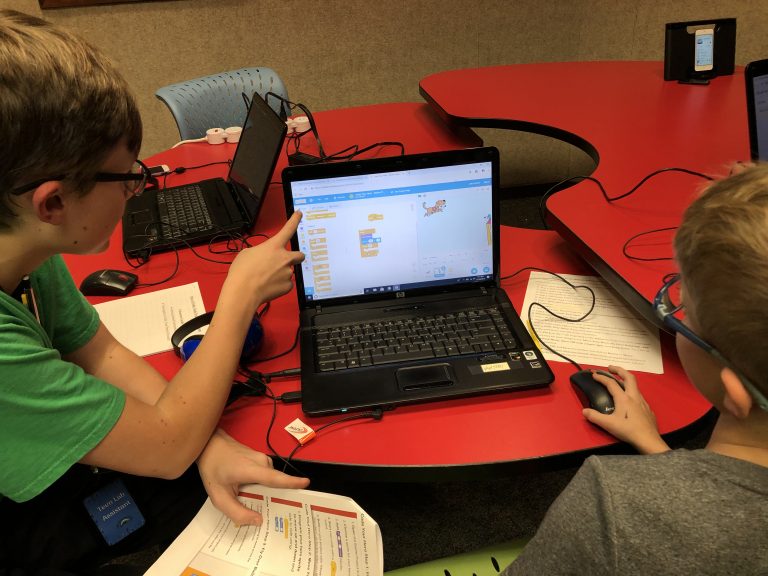 Two children using a coding program on a laptop.