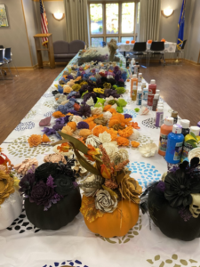 A table covered with art and craft supplies to make beautiful pumpkin table centerpieces