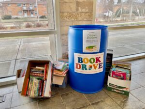 A bin for a book drive with several boxes full of books around it.