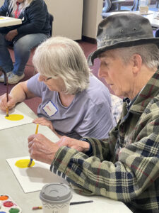 A photo of a couple painting during a Memory Café fall painting party at the Irvin L. Young Memorial Library in Whitewater.