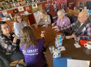 A photo of a group of people at a Memory Café playing a game with chocolates at a hot cocoa themed gathering at Paradiddle Café coffee shop in Waterloo.