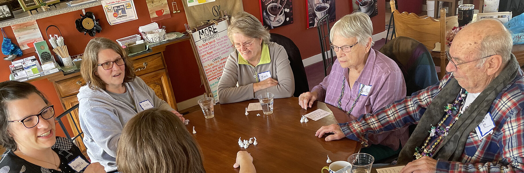 A photo of a group of people at a Memory Café playing a game with chocolates at a hot cocoa themed gathering at Paradiddle Café coffee shop in Waterloo.