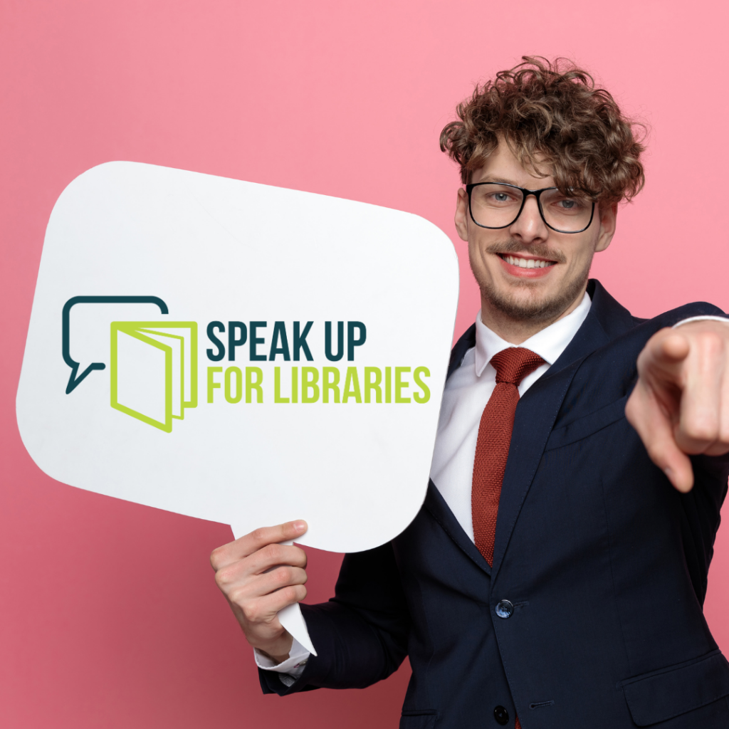 Person holding a sign in the shape of a speech bubble with the Speak Up For Libraries logo on it with a book icon overlapping a speech bubble icon.