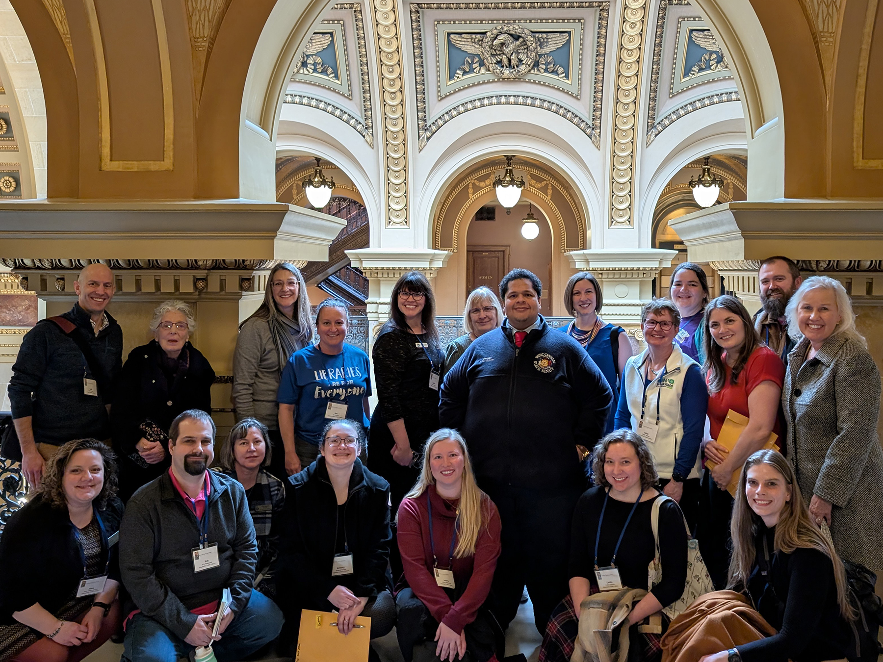 A large group of library staff and trustees with Senator Julian Bradley inside the Wisconsin State Capitol building in Madison.